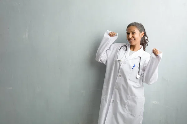Young indian doctor woman against a wall Listening to music, dancing and having fun, moving, shouting and expressing happiness, freedom concept
