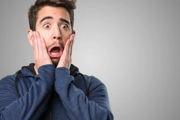 afraid young man on grey background