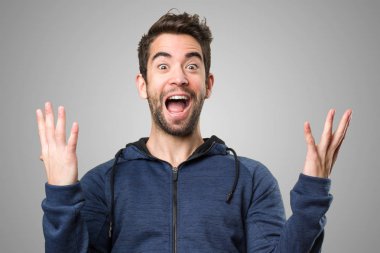 Genç adam gri arka plan üzerinde kazanan jest yapıyor