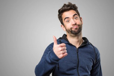 Genç adam gri arka plan üzerinde iyi jest yapıyor