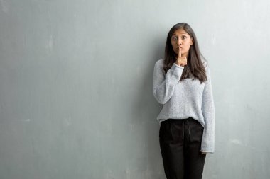 Genç Hintli kadın gizli tutmak veya soran sessizlik, ciddi bir yüz, itaat kavram için bir grunge duvara