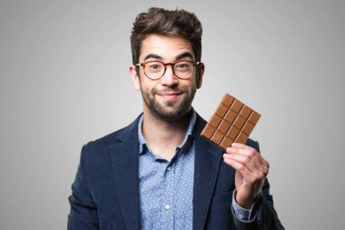 Genç adam bir çikolata gri arka plan üzerinde tutan