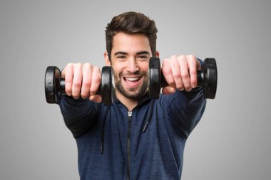 gri arka plan üzerinde halter kullanan genç adam