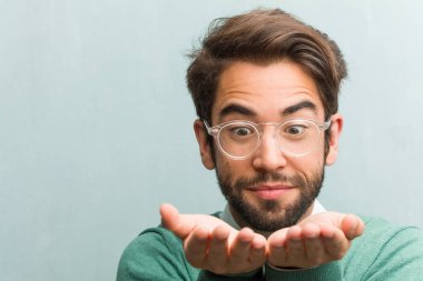Elleriyle bir şey tutan, bir ürün, gülümseyen ve neşeli gösterilen, hayali bir nesne sunan genç yakışıklı girişimci adam yüz portre