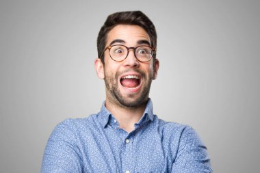 şaşırmış genç adam kollarını gri arka plan üzerinde geçiş