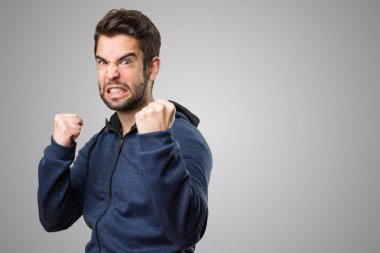 Genç adam gri arka plan üzerinde kazanan jest yapıyor