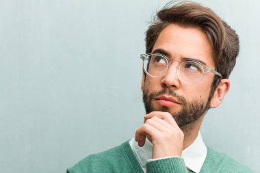 Genç yakışıklı girişimci adam yüz closeup düşünme ve bakılması, hakkında bir fikir, karışık bir çözüm bulmaya çalışırken