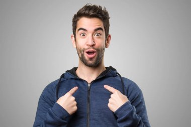 Genç adam kendini gri arka plan üzerine işaret