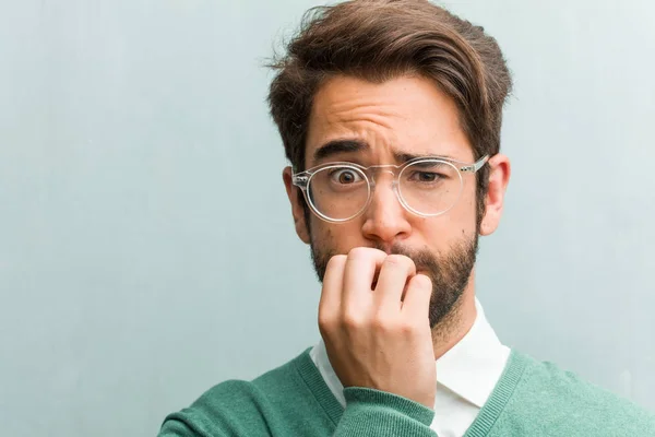 Young handsome entrepreneur man face closeup biting nails, nervous and very anxious and scared for the future, feels panic and stress