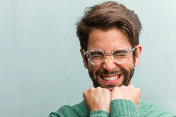 Young handsome entrepreneur man face closeup very happy and excited, raising arms, celebrating a victory or success, winning the lottery