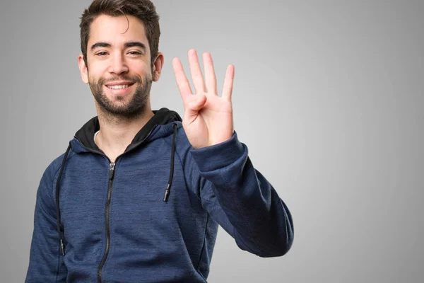 Νεαρός Άνδρας Κάνει Αριθμό Τέσσερα Χειρονομία Γκρίζο Φόντο — Φωτογραφία Αρχείου