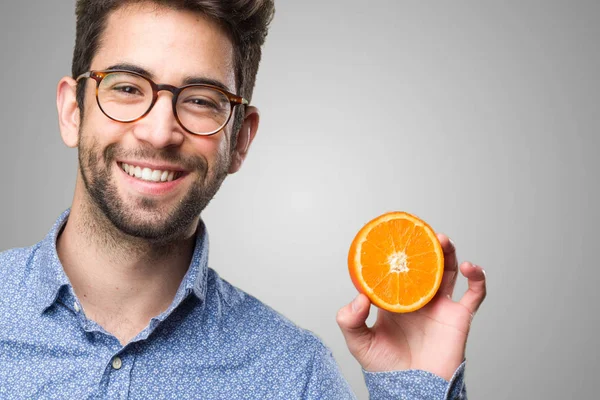 Joven Sosteniendo Una Naranja Sobre Fondo Gris —  Fotos de Stock