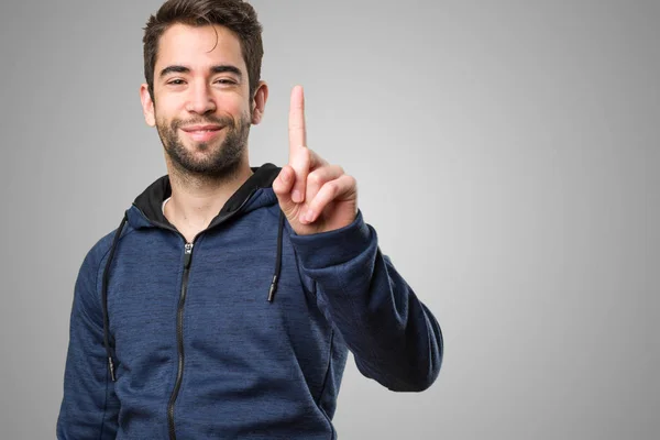 Junger Mann Macht Geste Nummer Eins Auf Grauem Hintergrund — Stockfoto