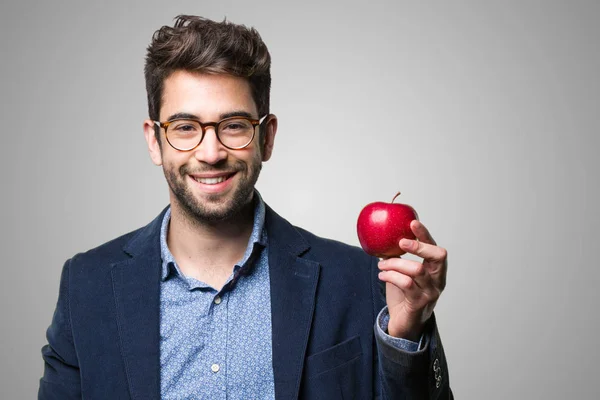 Joven Sosteniendo Una Manzana Roja Sobre Fondo Gris — Foto de Stock