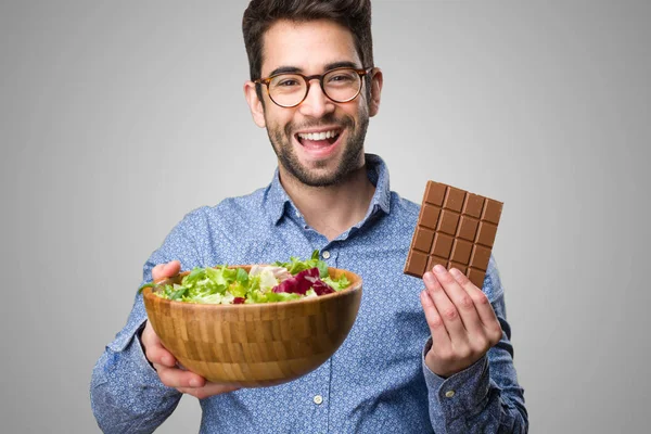 Joven Sosteniendo Una Ensalada Una Barra Chocolate Sobre Fondo Gris — Foto de Stock