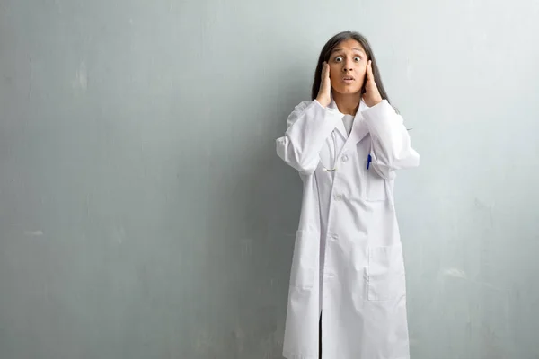 Young indian doctor woman against a wall covering ears with hands, angry and tired of hearing some sound