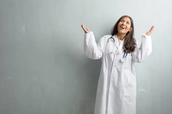 Young indian doctor woman against wall laughing and having fun