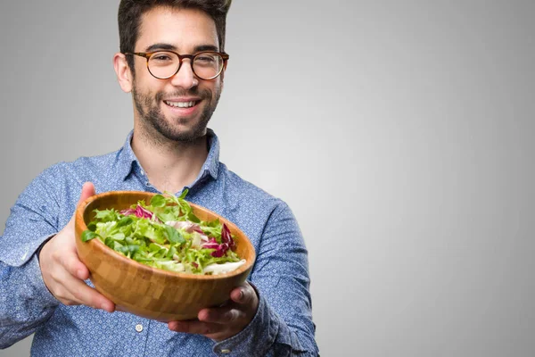 Joven Que Ofrece Ensalada Sobre Fondo Gris — Foto de Stock