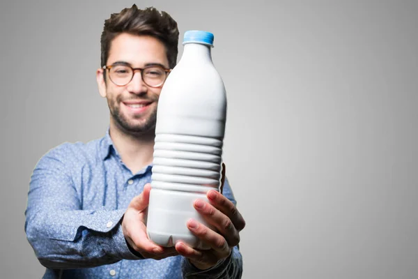 Jonge Man Het Aanbieden Van Een Fles Melk Grijze Achtergrond — Stockfoto