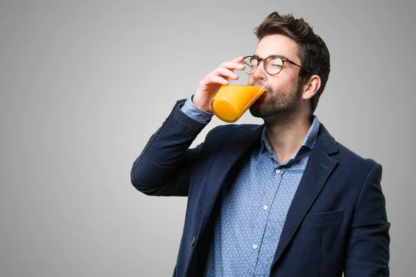 young man drinking a juice on grey background