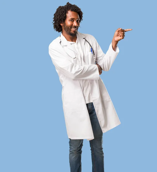 Красивий Афро Американський Лікар Вказує Бік Посміхаючись Здивовано Представляючи Щось — стокове фото