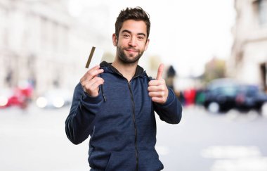 bir kredi kartı tutan ve iyi jest yapıyor genç adam arka plan bulanık