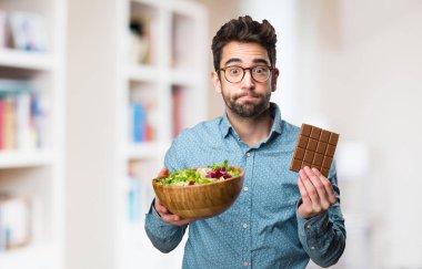 Genç adam bir salata ve çikolata üzerinde arka plan bulanık tutan
