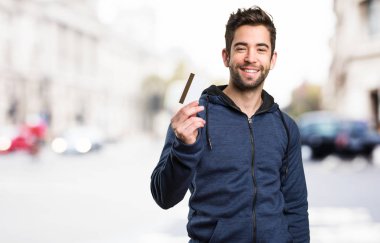 Genç adam bir kredi kartı üzerinde arka plan bulanık tutan