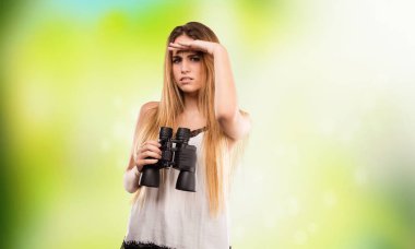 Genç ve güzel kadın üzerinde dürbün yeşil arka plan bulanık