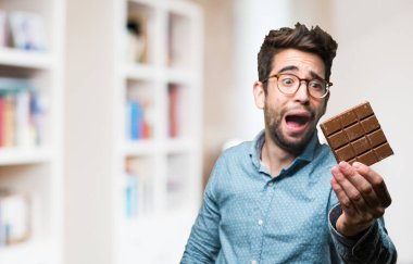 Genç adam bir çikolata üzerinde arka plan bulanık tutan