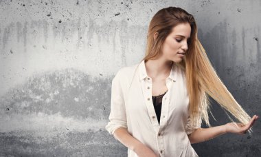 Genç ve güzel kadın saçlarını grunge gri arka plan üzerinde dokunmadan