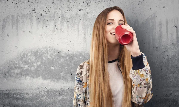 pretty young woman drinking soda drink on grunge grey background