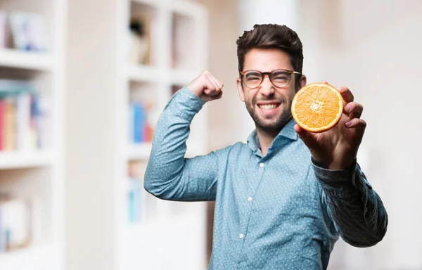 Stark Ung Man Innehar Apelsin Suddig Bakgrund — Stockfoto