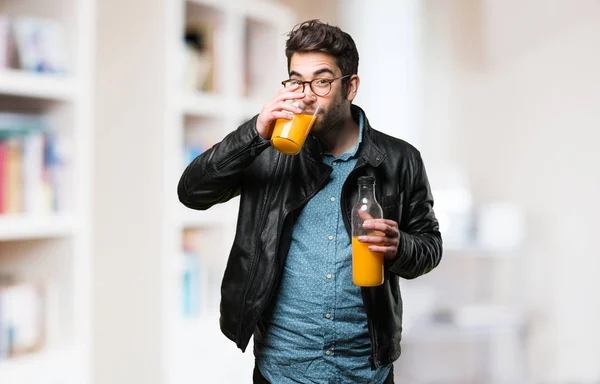 Ung Man Dricka Apelsinjuice Suddig Bakgrund — Stockfoto