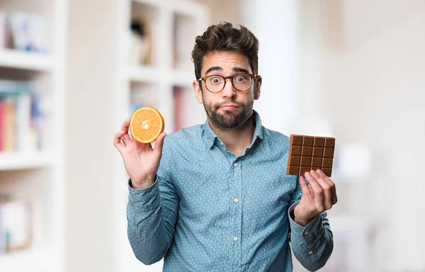 Joven Sosteniendo Una Naranja Una Barra Chocolate Sobre Fondo Borroso — Foto de Stock