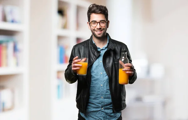 young man holding an orange juice bottle on blurred background