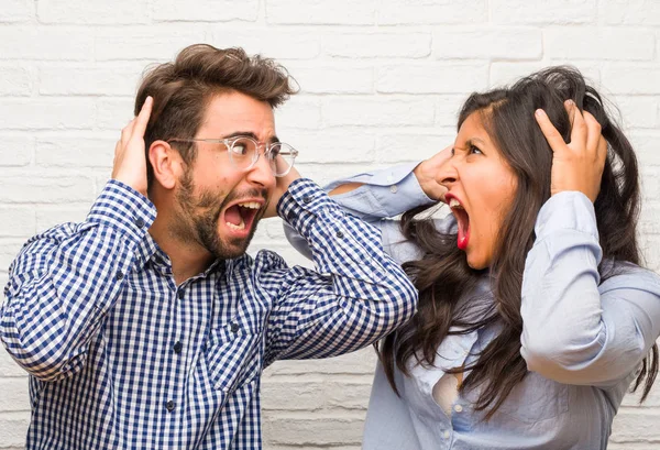 Young indian woman and caucasian man couple crazy and desperate, screaming out of control, funny lunatic expressing freedom and wild