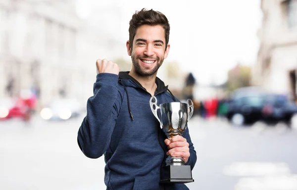 Mladý Muž Který Držel Trofej Dělá Vítěze Gesto Rozostřeného Pozadí — Stock fotografie