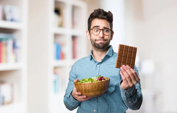 Joven Sosteniendo Una Ensalada Una Barra Chocolate Sobre Fondo Borroso — Foto de Stock