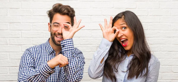 Young indian woman and caucasian man couple cheerful and confident doing ok gesture, excited and screaming, concept of approval and success