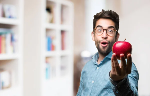 surprised young man holding an apple on blurred background
