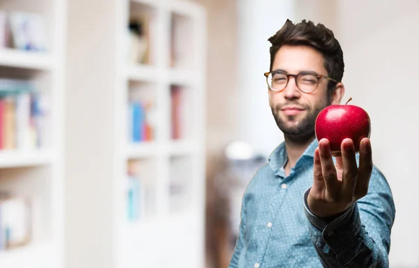 young man holding an apple on blurred background