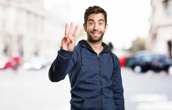 Jonge Man Doen Nummer Drie Gebaar Achtergrond Wazig — Stockfoto