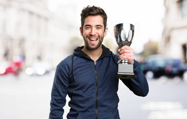 happy young man holding a trophy on blurred background