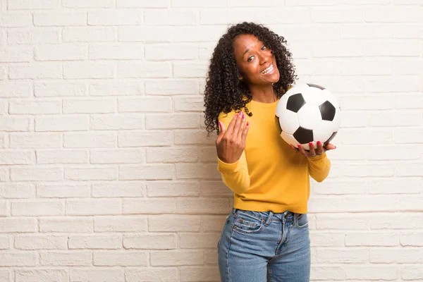 レンガの壁に来るに招待サッカー ボールで若い黒人女性 — ストック写真