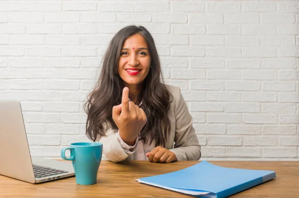 Young indian woman at office inviting to come, confident and smiling making gesture with hand, being positive and friendly