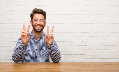 Eğlenceli ve mutlu, pozitif ve doğal yapıyor bir jest zafer, barış kavramı, oturan genç beyaz adam