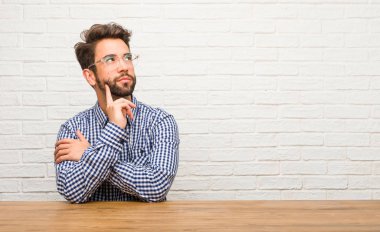 Düşünme ve bakılması, hakkında bir fikir, karışık oturan genç beyaz adam bir çözüm bulmaya çalışıyorum