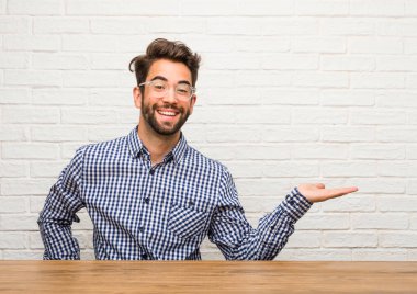 Beyaz delikanlı oturan elleriyle bir şey tutan, bir ürün, gülümseyen ve neşeli gösterilen, hayali bir nesne sunan