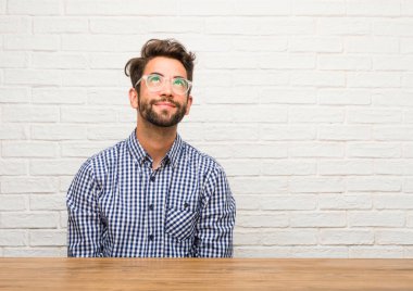 Ararken, bir şey eğlenceli düşünme ve bir fikir, hayal gücü, mutlu ve heyecanlı kavramı olan oturan genç beyaz adam